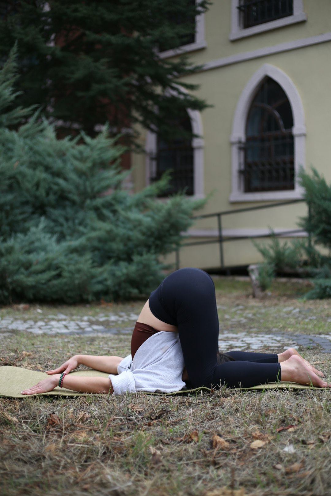 a-woman-laying-on-a-yoga-mat-in-front-of-a-building-t3kwkp-of38